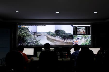 Officials from the Jakarta Sanitation Department monitor live feeds from closed circuit cameras installed along the Cilliwung river in Jakarta, Indonesia December 30, 2016. REUTERS/Fatima El-Kareem