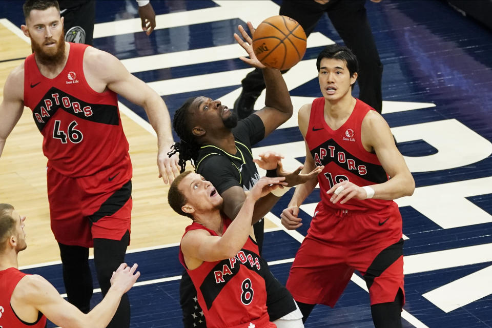 Minnesota Timberwolves' Naz Reid, center, battles for the rebound with Toronto Raptors' Malachi Flynn (8) in the first half of an NBA basketball game, Friday, Feb. 19, 2021, in Minneapolis. (AP Photo/Jim Mone)