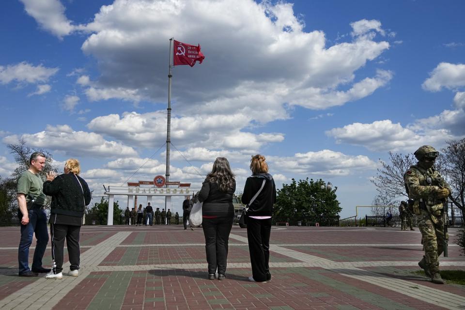 FILE - People look at a replica of the Victory banner fluttering in the wind over the central square in Melitopol, Zaporizhzhia region, in territory under Russian military control, southeastern Ukraine, May 1, 2022. Some in the West think Russian President Vladimir Putin may use the Victory Day on May 9 when Russia celebrates the defeat of Nazi Germany in World War II to officially declare that war is underway in Ukraine and announce a mobilization _ the claim rejected by the Kremlin. (AP Photo/Alexander Zemlianichenko, File)