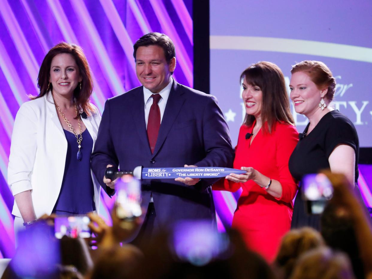 Moms for Liberty founders Tiffany Justice (L) and Tina Descovich present the Liberty Sword to Governor Ron DeSantis before he speaks during the inaugural Moms For Liberty Summit at the Tampa Marriott Water Street on July 15, 2022 in Tampa, Florida.