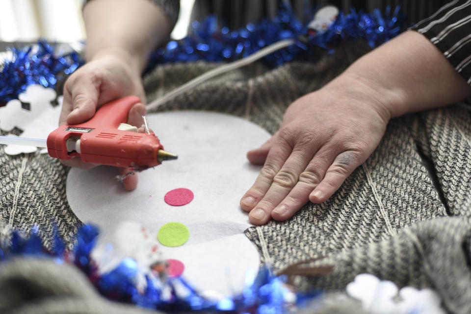 Doris Cochran works on "an ugly sweater," which she is planning to sell, Friday, Jan. 18, 2019 in her apartment in Arlington, Va., Cochran is a disabled mother of two young boys living in subsidized housing in Arlington, Virginia. She’s stockpiling canned foods to try to make sure her family won’t go hungry if her food stamps run out. She says she just doesn’t know “what’s going to happen” and that’s what scares her the most. (AP Photo/Sait Serkan Gurbuz)