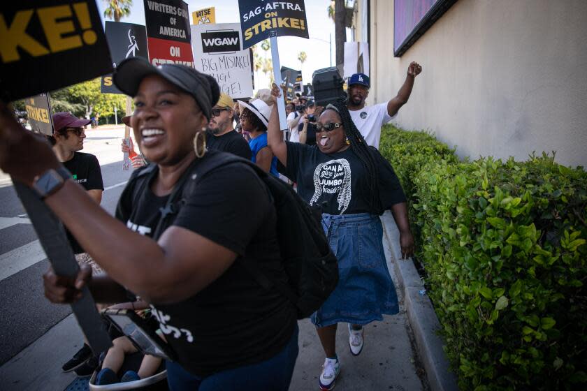 Burbank, CA - July 28: Danielle Pinnock (second from left) and Lanisa Frederick (left), two black actors who are part of "Hashtag Booked" a groundbreaking online series, dance down the street to the song "fight the Power" as they picket outside of the Warner Brothers Lot as the Hollywood strike continues on Friday, July 28, 2023 in Burbank, CA. (Jason Armond / Los Angeles Times)