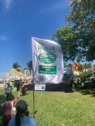 A flag bearing the Publix logo and an image of a watermelon was used Saturday to call attention to farmworkers wages at a protest in Palm Beach.