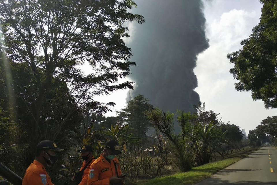 Rescue workers stand as thick smoke billows from a fire that razes through Pertamina Balongan Refinery in Indramayu, West Java, Indonesia, Monday, March 29, 2021. Hundreds of people living in villages around the refinery have been evacuated following the fire that broke out after midnight on Monday. (AP Photo)