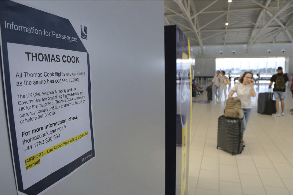 A woman passes by a notice of informations for Thomas Cook passengers is seen on a wall at Larnaca airport in the eastern Mediterranean island of Cyprus, Monday, Sept. 23, 2019. The collapse of tour operator Thomas Cook will strike a major blow to the Cypriot tourism industry. (AP Photo/Petros Karadjias)