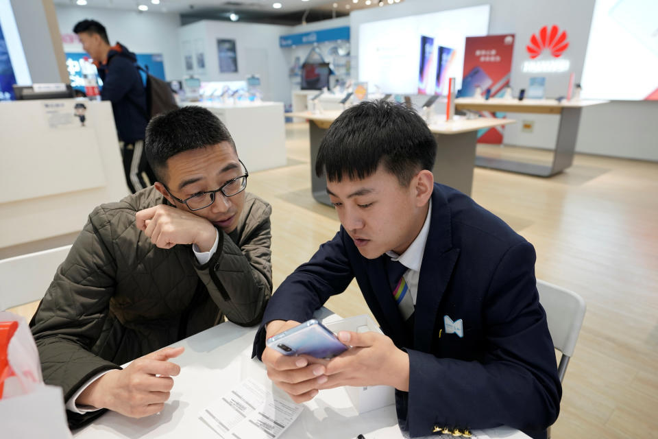 A salesman shows a new Huawei P30 smartphone to a customer after Huawei's P30 and P30 Pro went on sale at a Huawei store in Beijing, China, April 11, 2019. REUTERS/Jason Lee