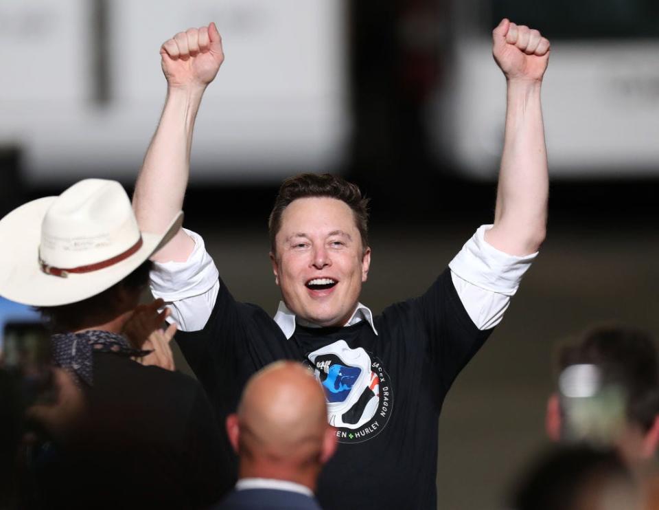 Elon Musk cheering with his arms in the air.