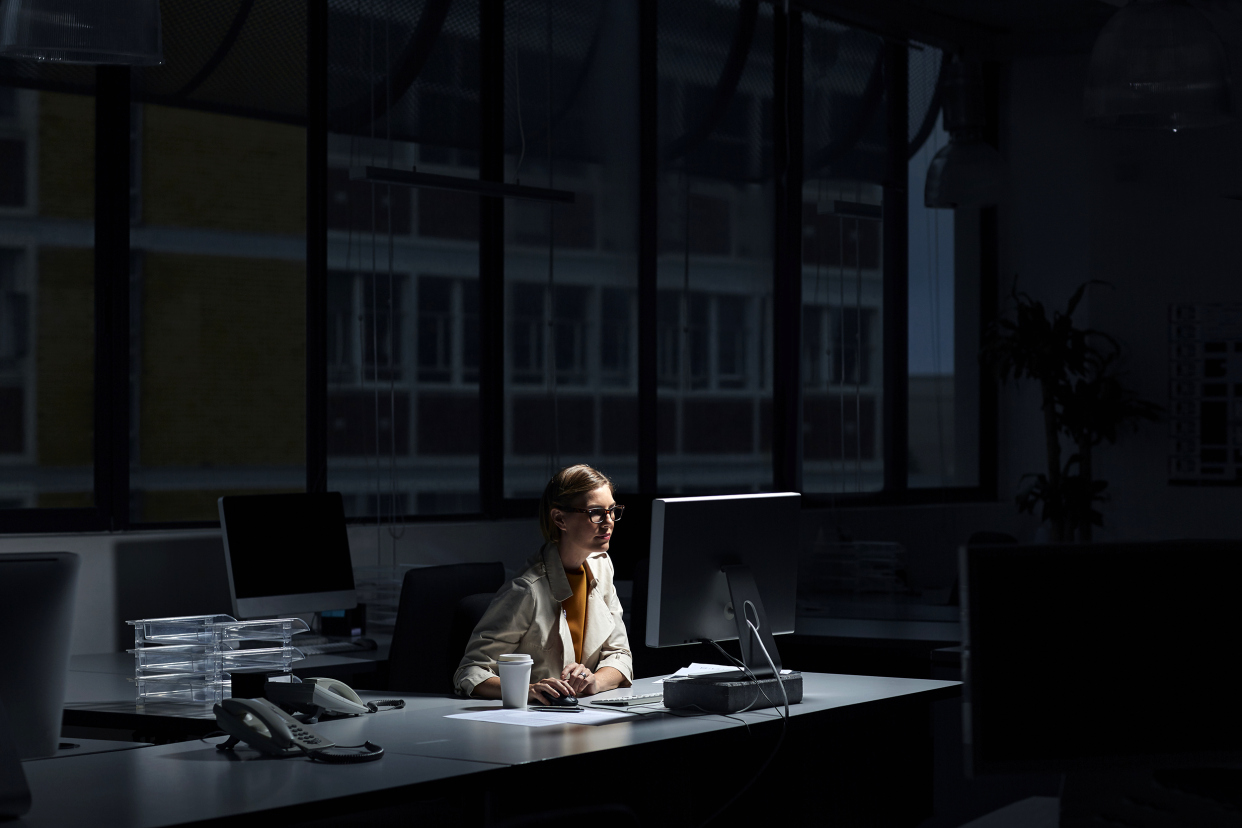 Woman working overtime in a dark office at night