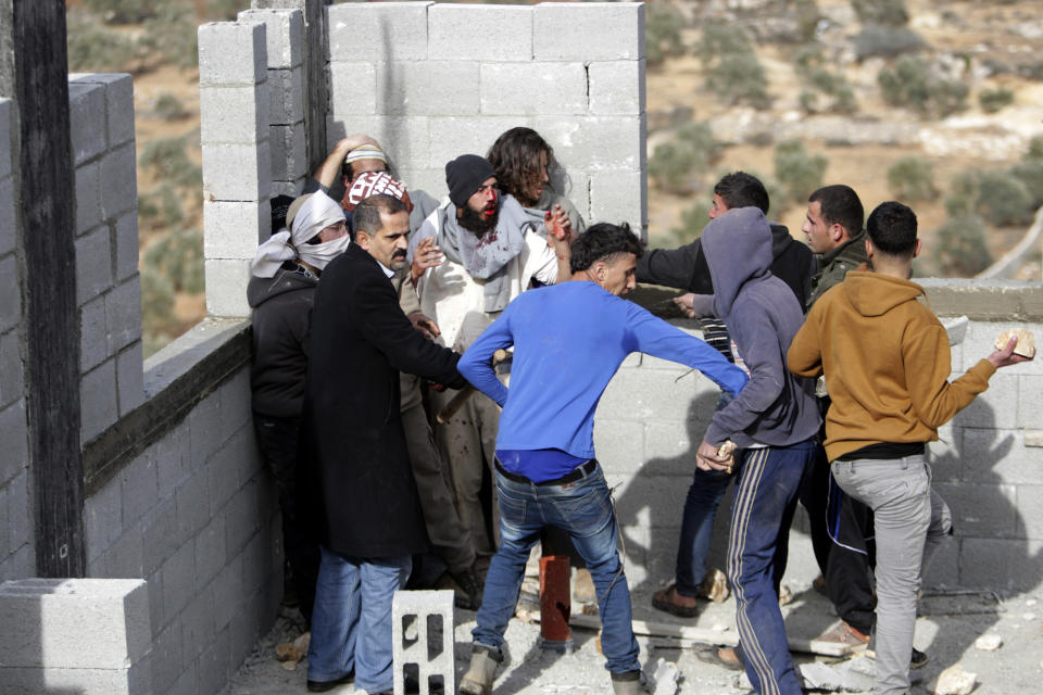 FILE - In this file photo taken Tuesday, Jan. 7, 2014, some Palestinians try to keep others from further injuring Israeli settlers who are being detained by Palestinian villagers in a building under construction near the West Bank village of Qusra, southeast of Nablus. The annual rate of Israeli settler attacks against Palestinians has almost quadrupled in eight years, U.N. figures show, buttressing claims that Israeli security forces have largely failed to stem the so-called "price tag" campaign in which thugs cut down trees, deface mosques and beat Palestinian farmers. (AP Photo/Nasser Ishtayeh, File)