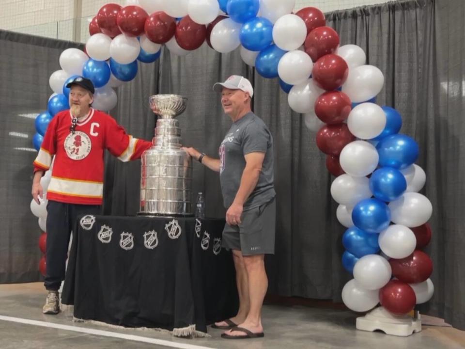 Colorado Avalanche assistant coach Ray Bennett, right, brought the Stanley Cup to his hometown of Innisfail, Alta., on Monday. Local residents like Rob Hamill, left, got a once-in-a-lifetime oportunity to stand next to the legendary trophy.  (Dan McGarvey/CBC - image credit)
