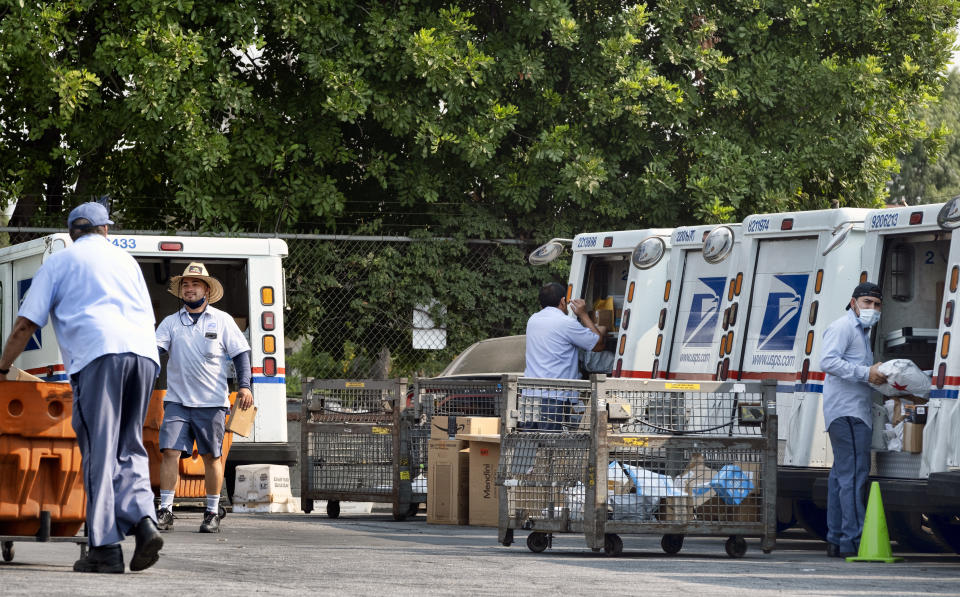 Postal workers load their mail delivery vehicles at the Panorama city post office on Thursday, Aug. 20, 2020 in the Panorama City section of Los Angeles. The Postmaster general announced Tuesday he is halting some operational changes to mail delivery that critics warned were causing widespread delays and could disrupt voting in the November election. Postmaster General Louis DeJoy said he would "suspend" his initiatives until after the election "to avoid even the appearance of impact on election mail." (AP Photo/Richard Vogel)