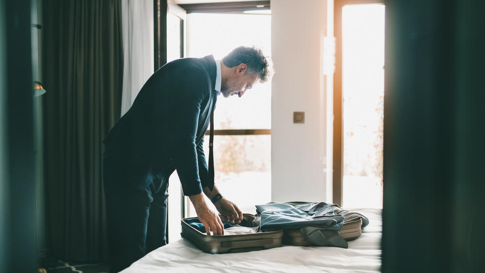 Handsome mature businessman taking his jacket off in a hotel room.