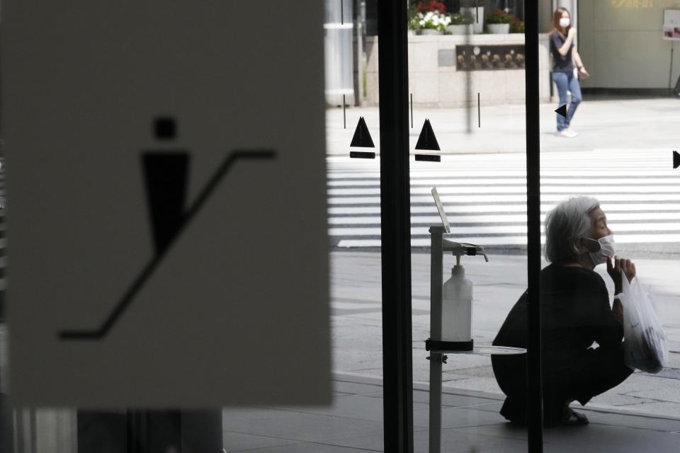 A woman wearing a protective mask to help curb the spread of the coronavirus takes shelter in the shade from high temperature Thursday, July 29, 2021, in Tokyo. (AP Photo/Eugene Hoshiko)