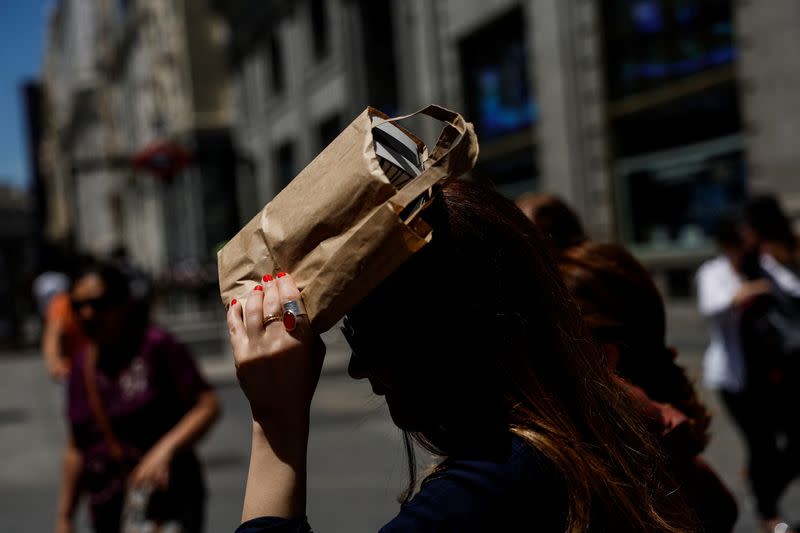 Una mujer se cubre la cabeza con un bolso durante un día caluroso en Madrid, España.