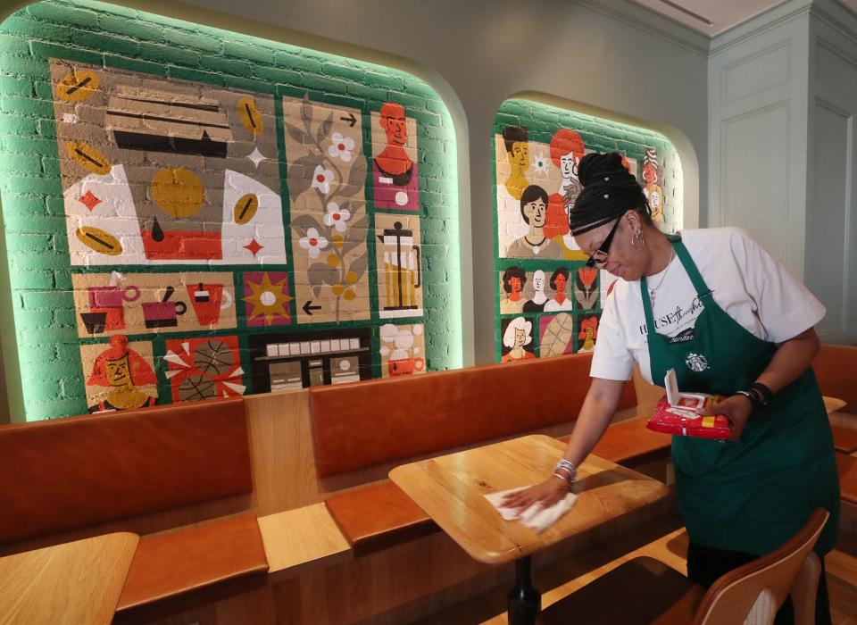 Sundae Davenport, one of the workers at Starbucks, wipes off a table in the coffeeshop during House Three Thirty's official opening day on Thursday.