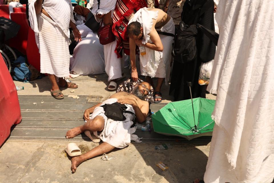 A man, affected by the scorching heat, is helped by another Muslim pilgrim as they arrive to perform the symbolic 'stoning of the devil' ritual during the annual hajj pilgrimage in Mina (AFP via Getty Images)