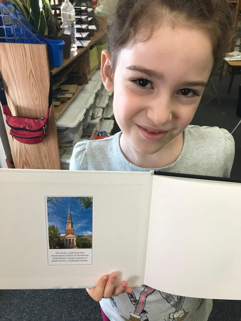 Avigail Avram-Carmi is a student at the Montessori Academy in Mishawaka. Here, she displays the note about the teacher Sarah Proctor in her copy of religious educator and Mishawaka resident Phyllis Wezeman's “Petra’s Pier Picnic.” Wezeman has been visiting local classrooms and giving away copies of the book about combating hunger in memory of Proctor, who died Dec. 2, 2022, in a car accident.