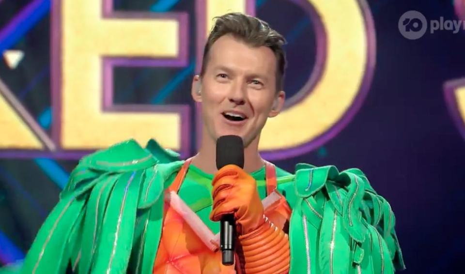 A photo of ex-cricketer Brett Lee in a parrot costume on stage of The Masked Singer in episode two.