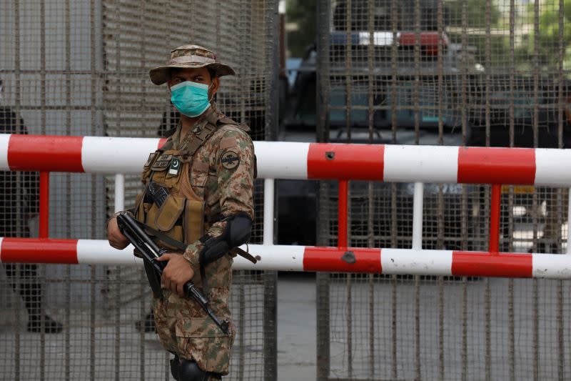 Army soldier wears protective mask as he stands guard at the entrance of the Pakistan Stock Exchange, day after an attack in Karachi