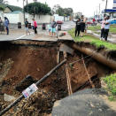 People stand on a damaged road after massive flooding in Amanzimtoti, near Durban, South Africa April 23, 2019 in this picture obtained from social media on April 24, 2019. Gavin Welsh via REUTERS