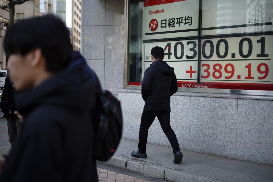 A person walks in front of an electronic stock board showing Japan's Nikkei 225 index at a securities firm Monday, March 4, 2024, in Tokyo. Japan's Nikkei 225 share benchmark has topped 40,000 for the first time as strong demand for technology shares keeps pushing the index higher.(AP Photo/Eugene Hoshiko)