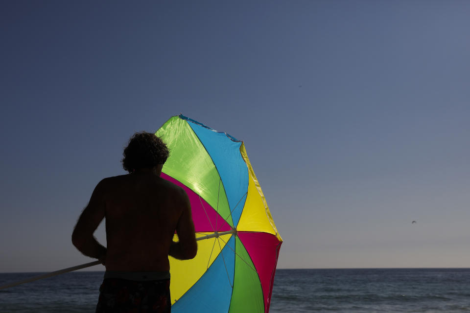 FILE - A man folds his umbrella on the beach Tuesday, Aug. 7, 2018, in Laguna Beach, Calif. Environmental advocates are celebrating in Laguna Beach _ but it won't be with balloons. The hilly, seaside city is weighing a plan to ban the sale and public use of balloons to curtail the risk of devastating wildfires and eliminate a major source of trash floating near the community's scenic shores. (AP Photo/Jae C. Hong, File)