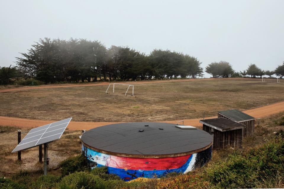 A water storage tank sits beside a dried field at Mendocino High School.