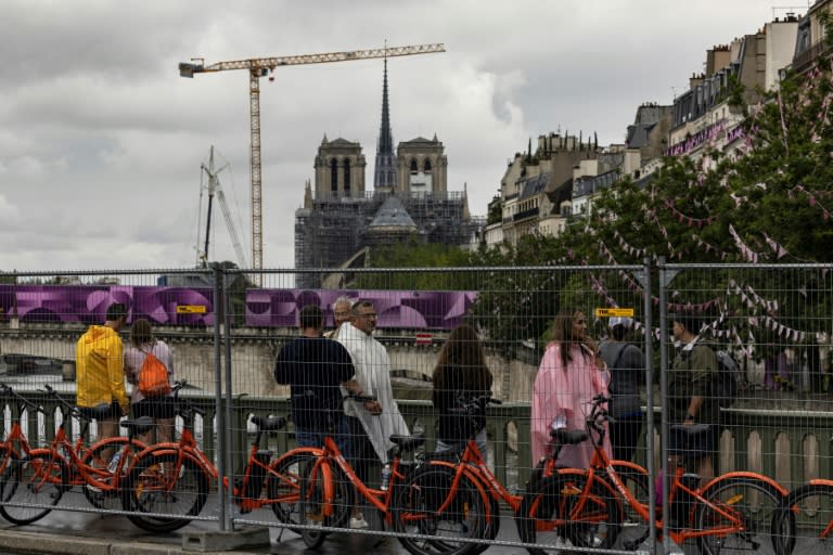 Turistas caminan al costado de las barreras de seguridad cerca de la catedral de Notre Dame a pocas horas del inicio de la ceremonia inaugural de los Juegos Olímpicos de París-2024 el 26 de julio de 2024 (JOEL SAGET)