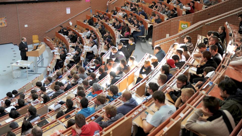 Erstsemester sitzen in einem Hörsaal der Universität und nehmen an der Einführungsveranstaltung in Maschinenbau teil.