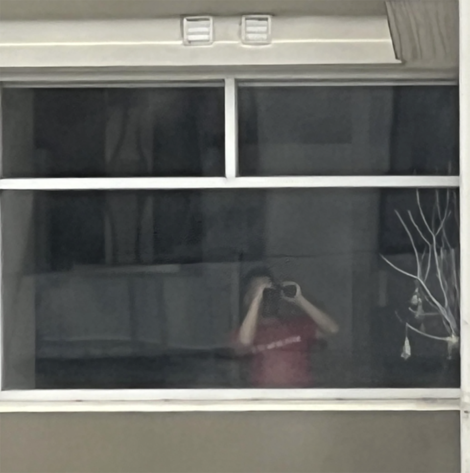 The male neighbour wearing a red shirt and holding binoculars looking through the tenant's window. 