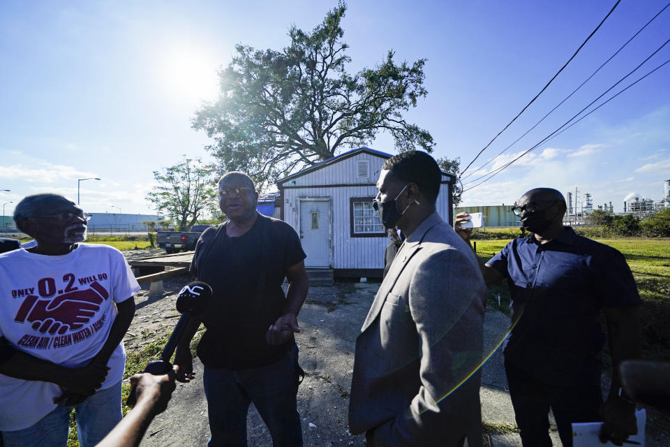 EPA Administrator Michael Regan, second right, talks with Michael Coleman, second left, in front of his house, which abuts the Marathon Petroleum Refinery and a Cargill grain depot, as he tours Reserve, La., Tuesday, Nov. 16, 2021. Coleman's house is the last one standing on his tiny street, squeezed between a sprawling oil refinery whose sounds and smells keep him up at night and a massive grain elevator that spews dust that covers his pickup and, he says, exacerbates his breathing problems. (AP Photo/Gerald Herbert)