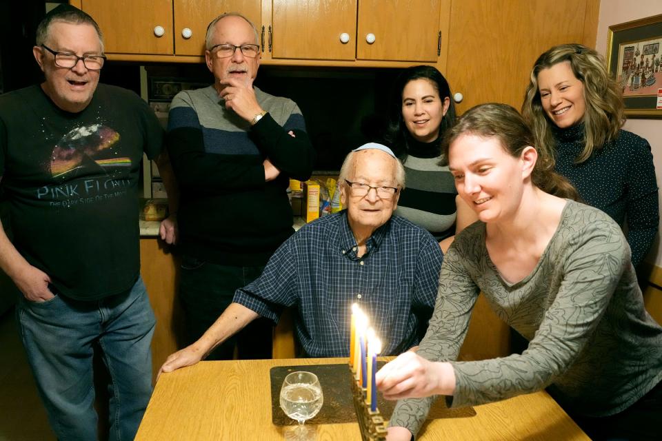 Albert Beder, a Holocaust survivor, watches his great niece Bekki Schnoll light the menorah while celebrating Hanukkah with family in Bayside on Tuesday, Dec. 12, 2023. Pictured are, from left, his sons, Rick and Gary Beder, his daughter, Melissa Spanjar, his granddaughter Joy O’Brien (far right), and Schnoll, lighting the candle. - Mike De Sisti / Milwaukee Journal Sentinel