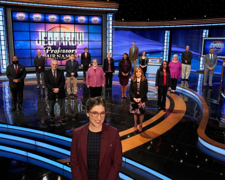 Mayim Bialik, host of 'Jeopardy!' stands on set in front of 15 contestants on its first-ever "Professors Tournament"