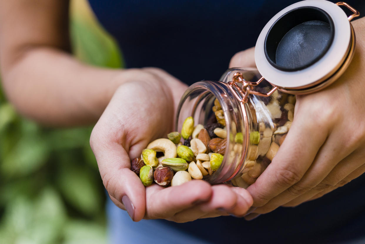 Brunette model hand holding glass hermetic pot with mix of nuts. plant proteins