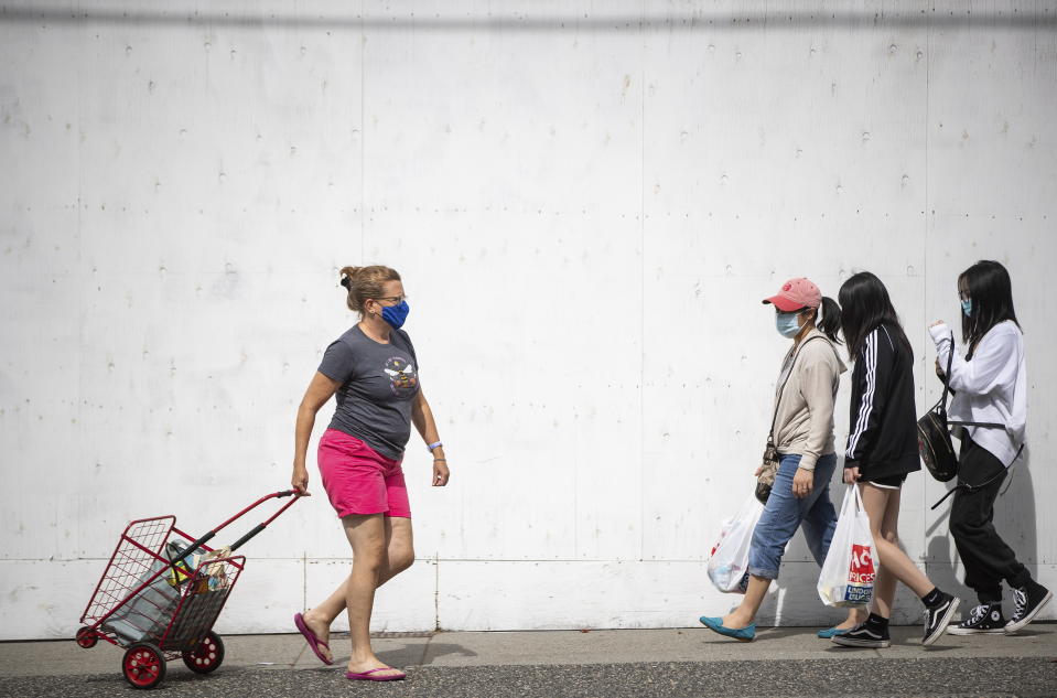 People wear face masks to curb the spread of COVID-19 while walking in Vancouver, British Columbia., Sunday, Aug. 30, 2020. (Darryl Dyck/The Canadian Press via AP)