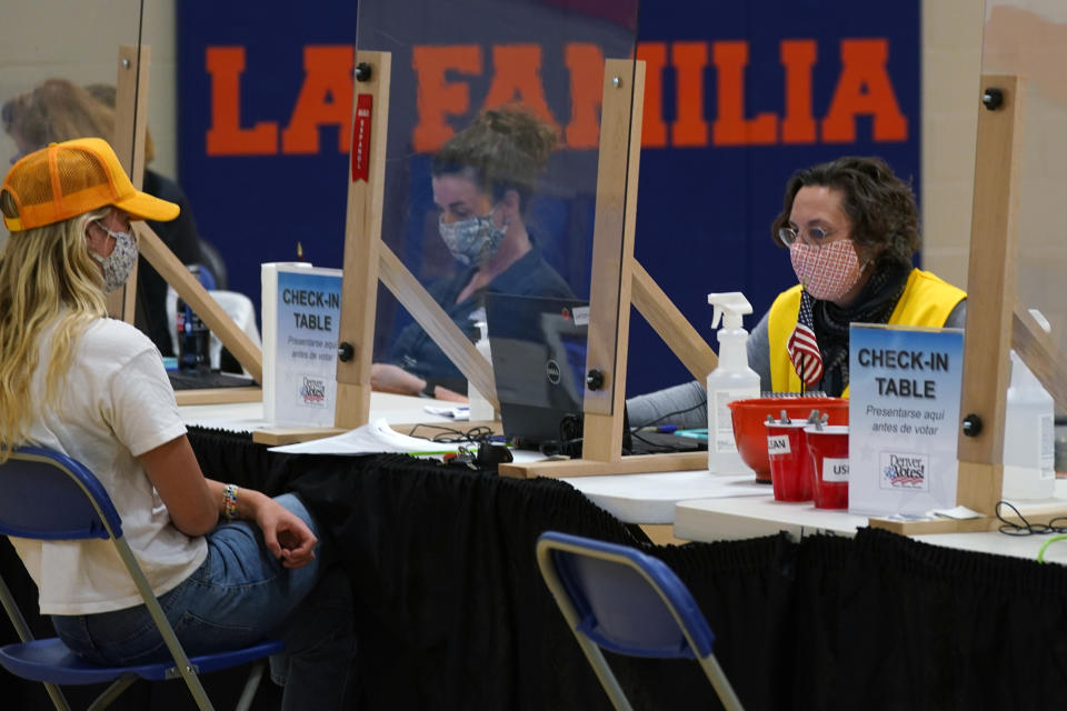 FILE - In this Tuesday, Nov. 3, 2020 file photo, an election judge checks in a voter at the La Familia Recreation Center in the Baker neighborhood south of downtown Denver. On Friday, April 9, 2021, The Associated Press reported on stories circulating online incorrectly asserting Major League Baseball had moved the All-Star game to Colorado because Georgia now requires an ID to vote, and yet Colorado also requires voter ID. But Colorado does not require an identification card to vote. Furthermore, Georgia already had a voter photo ID requirement, new sweeping rules include ID requirements to apply for a mailed ballot. (AP Photo/David Zalubowski)