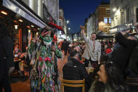People sit at setup tables outside pubs in Soho, in London, on the day some of England's third coronavirus lockdown restrictions were eased by the British government, Monday, April 12, 2021. Pubs, shops and hairdressers have opened as lockdown restrictions are eased Monday. (AP Photo/Alberto Pezzali)