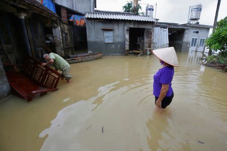 A man (L) cleans a chair at his submerged house after a heavy rain caused by a tropical depression in Hanoi, Vietnam October 16, 2017. REUTERS/Kham