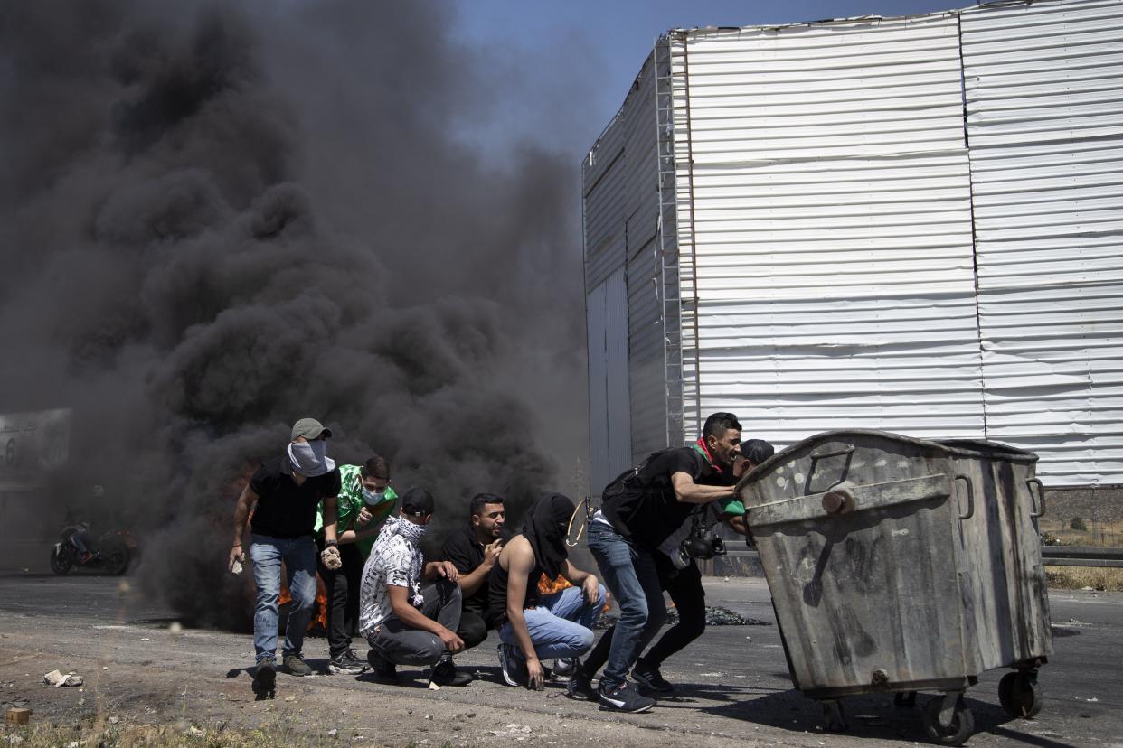 Palestinian demonstrators take cover during clashes with Israeli forces at the Hawara checkpoint, south of the West Bank city of Nablus, Friday, May 14, 2021. Health officials say several Palestinians were killed by Israeli army fire, at protests that took place in several locations across the West Bank of Friday.