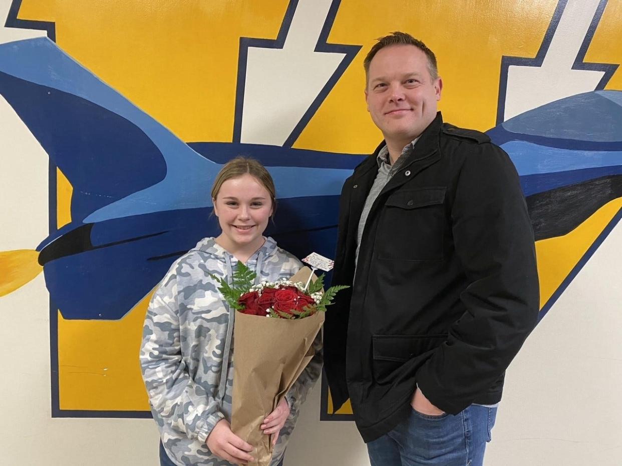 Abby Hill, an 8th grader at Wagar Middle School, holds a bouquet of red roses she received from Ryan Nissley, pastor of Grace Church in Flat Rock, for raising $1,300 to pay for toys to be distributed to the needy this week at Community Lutheran Church in Flat Rock.