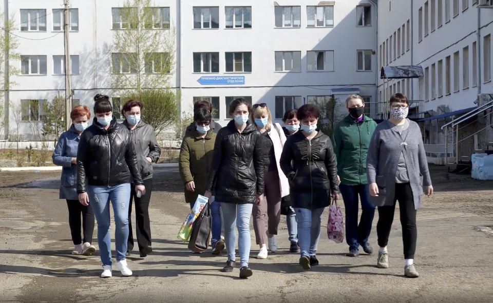 In this photo taken from video footage, nurses and orderlies walk to meet journalists in front of a hospital in Russia's Siberian city Chita, Russia, Saturday, May 16, 2020. Dozens of medical workers all across the country, from Siberia to southern Russia, made similar videos over the weekend, demanding the bonuses President Vladimir Putin promised them for working with coronavirus patients. Many said they had received 10 to 100 times less than was promised. (AP Photo/Konstantin Vasilyev)