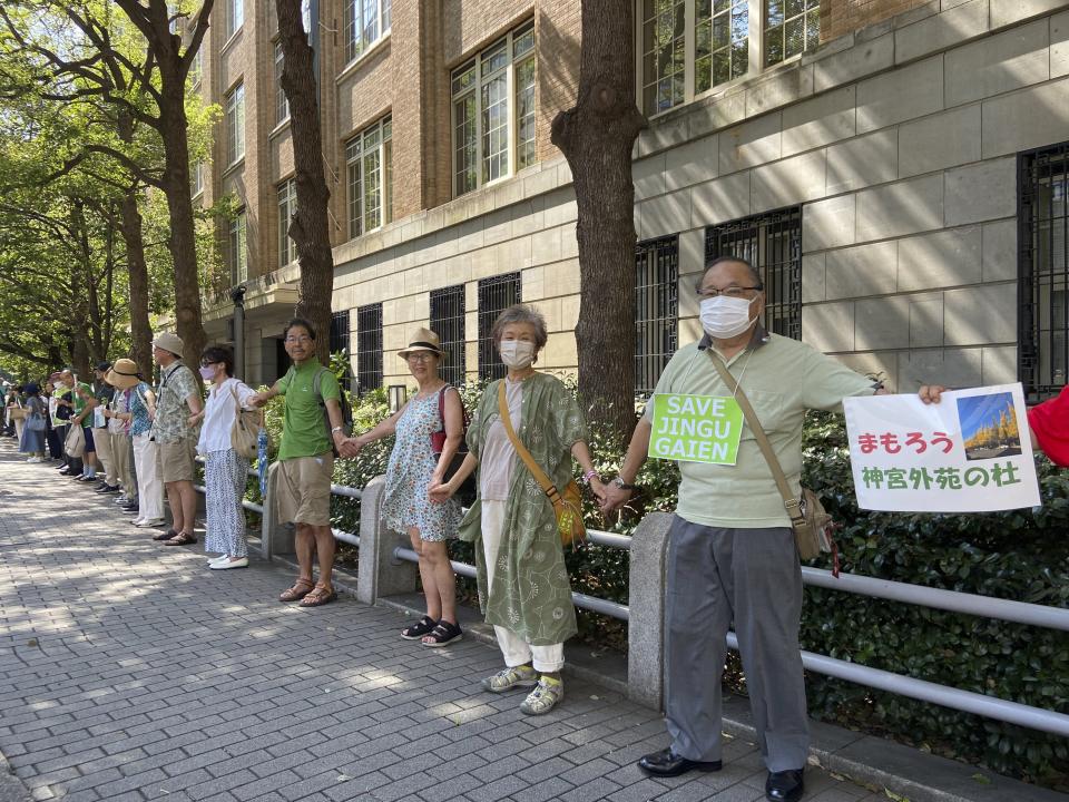 People form a human chain outside of the Ministry of Education, Culture, Sports, Science and Technology on Sunday, Sept. 17, 2023, demanding it scrap a controversial redevelopment of Tokyo’s beloved Jingu Gaien park area, part of whose land is owned by an independent sports promotion unit overseen by the ministry, in Tokyo, Japan.(AP Photo/Mari Yamaguchi)