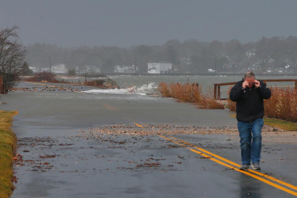 A man walks up Smith Neck Road in Dartmouth which was completely flooded due to the storm which struck the region.