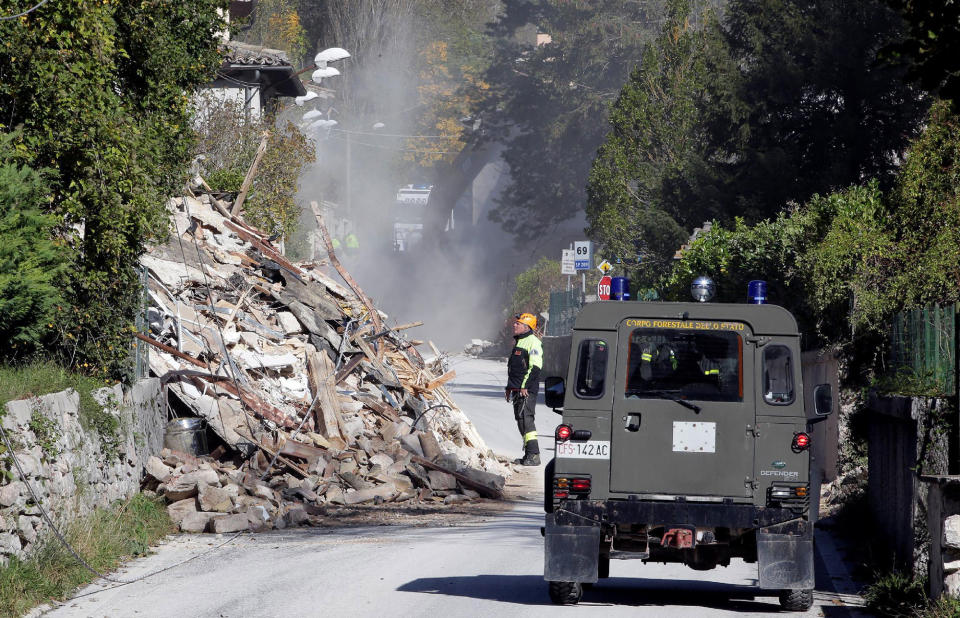 A firefighter looks at a collapsed building