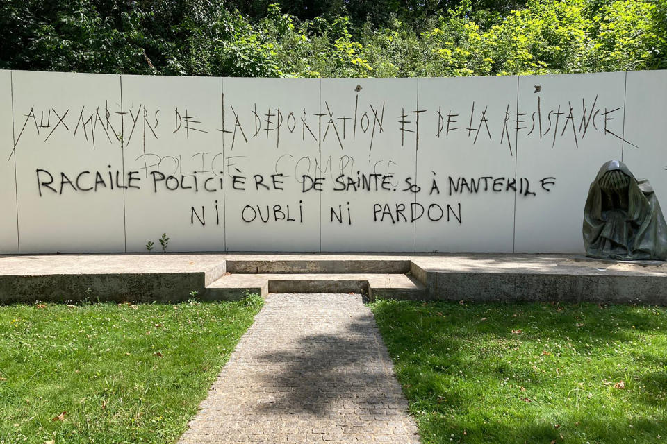 A graffiti reading "Police scum from Saint-Soline to Nanterre - do not forget or forgive" on a monument commemorating Holocaust victims and members of the French resistance memorial, Sunday, July 2, 2023 in Paris suburb Nanterre. In Nanterre, a monument commemorating Holocaust victims and members of the French resistance during World War II was defaced with graffiti Sunday, after it has been vandalized Thursday on the margins of a silent march to pay tribute after the police killing of a teenager. (AP Photo/Cara Anna)