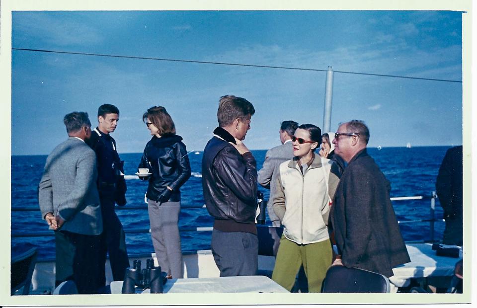 A regular in Camelot, Plimpton, far left, chats with Jackie Kennedy at a sailing race as President John F. Kennedy, center, talks with other fans.