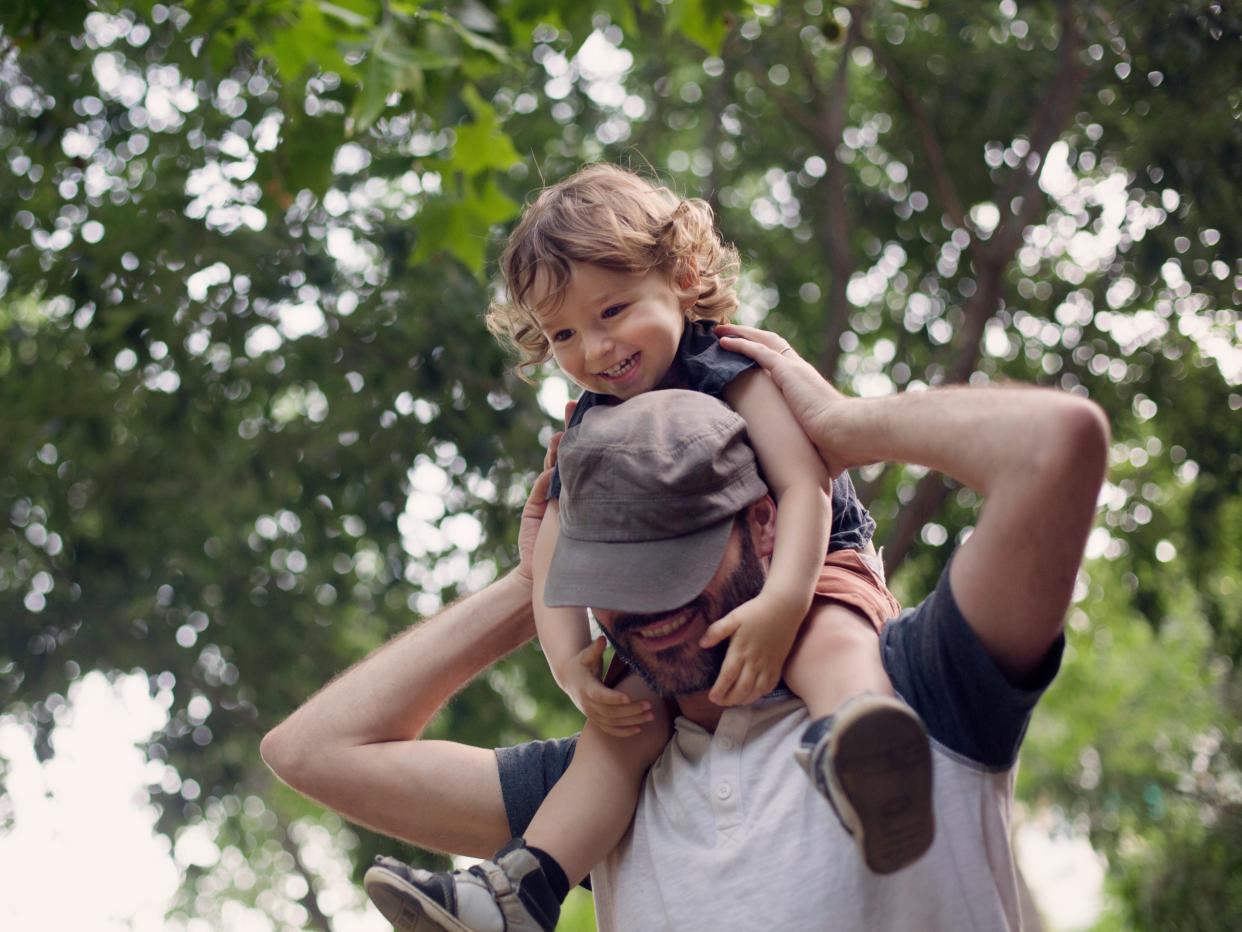 Dad carries boy in shoulders both looking happy