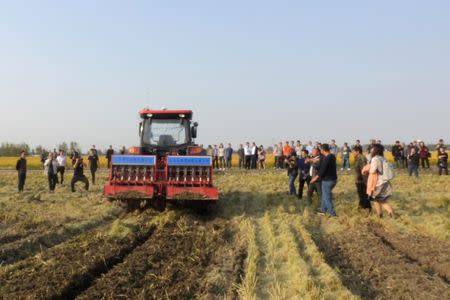 People surround an automated tractor working on a field during a trial in Xinghua, Jiangsu province, China October 29, 2018. Picture taken October 29, 2018. REUTERS/Hallie Gu