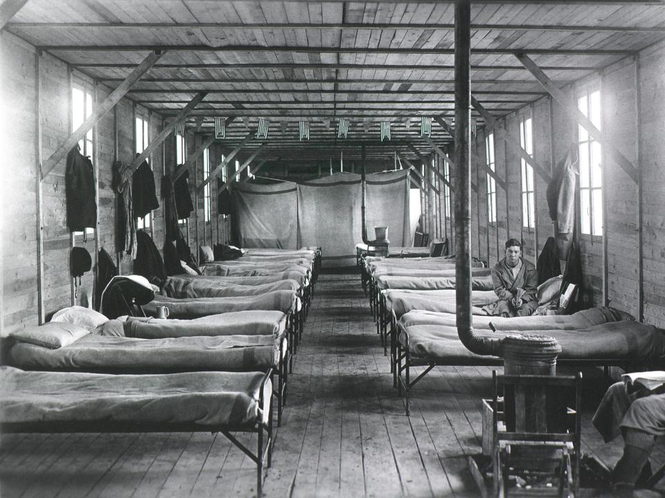 A photo of a young shoulder in an army camp in a barrack with empty cots.