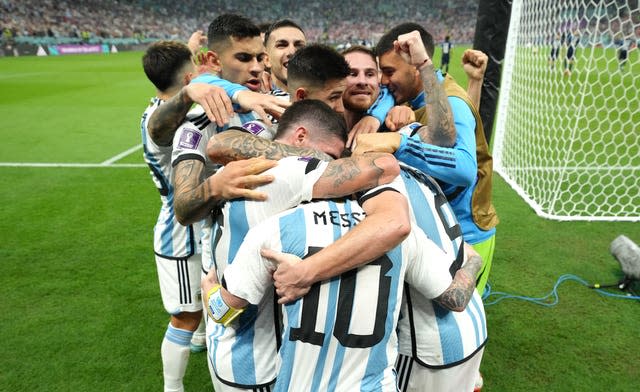 Argentina embrace Lionel Messi after he set up their third goal for Julian Alvarez
